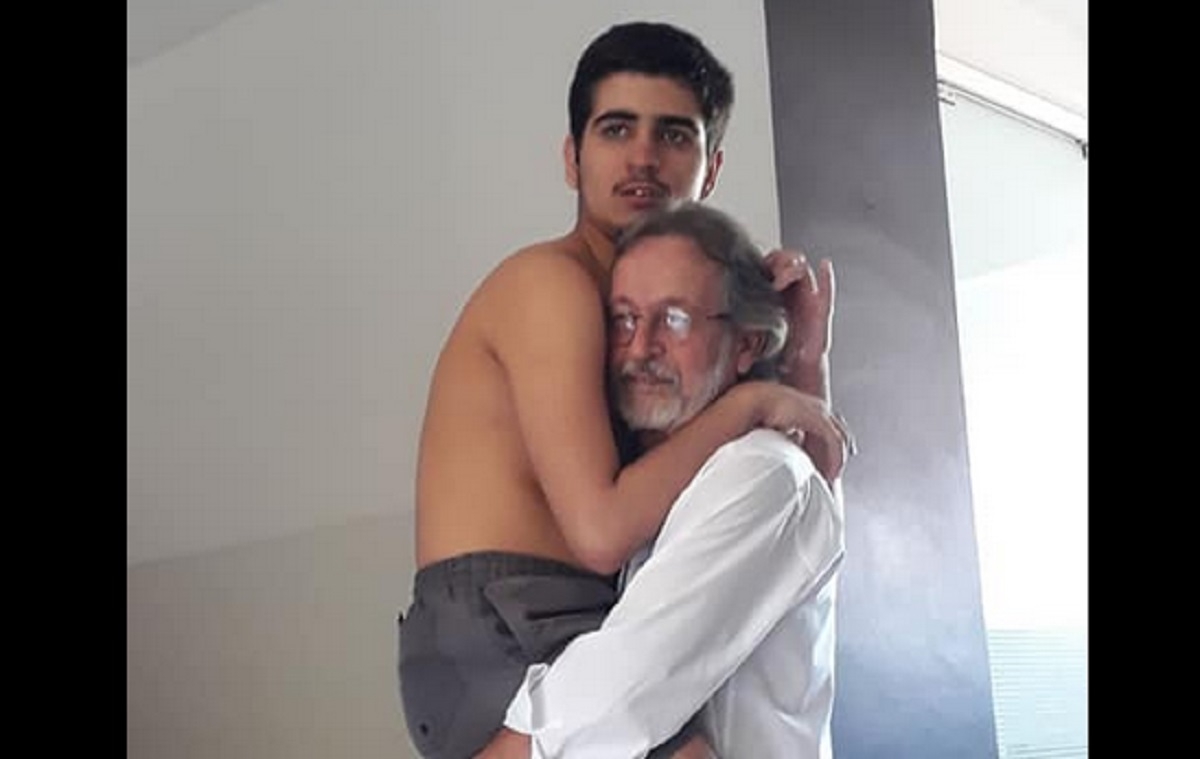 Un grand-père porte dans ses bras son petit-fils autiste âgé de 17 ans
